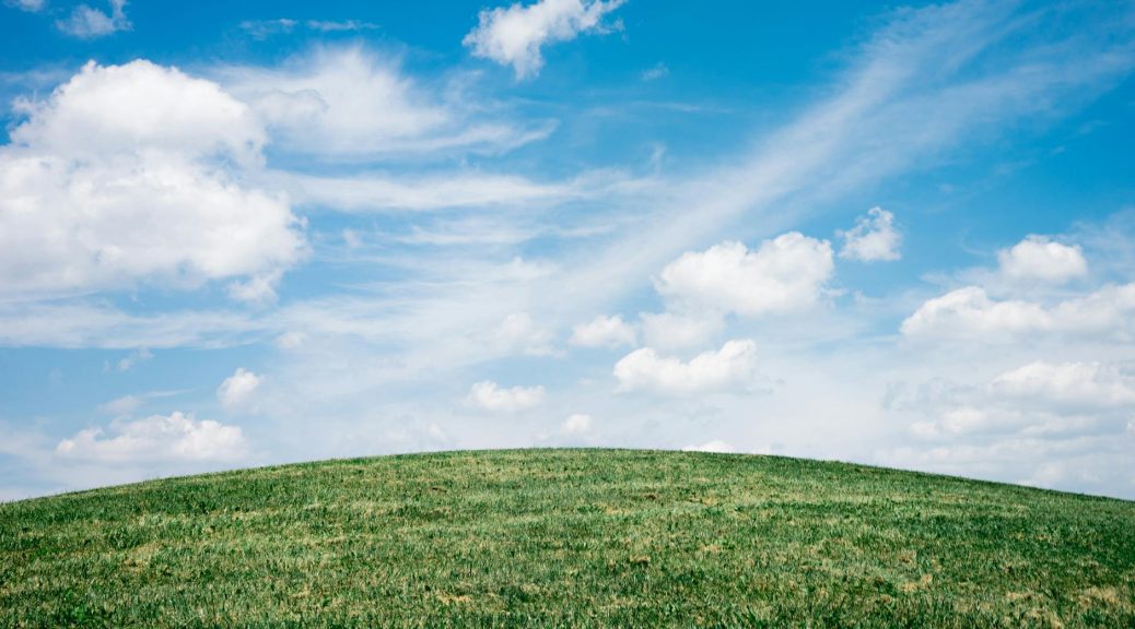 green grass field under white clouds