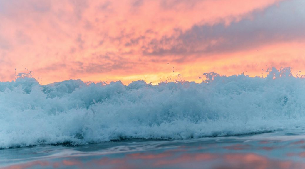 foamy sea under colorful sky at sunset